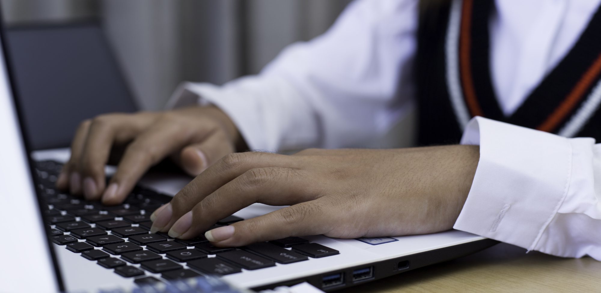 Hands typing on laptop keyboard &ndash; AI in education