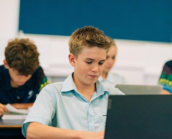 student in uniform using laptop